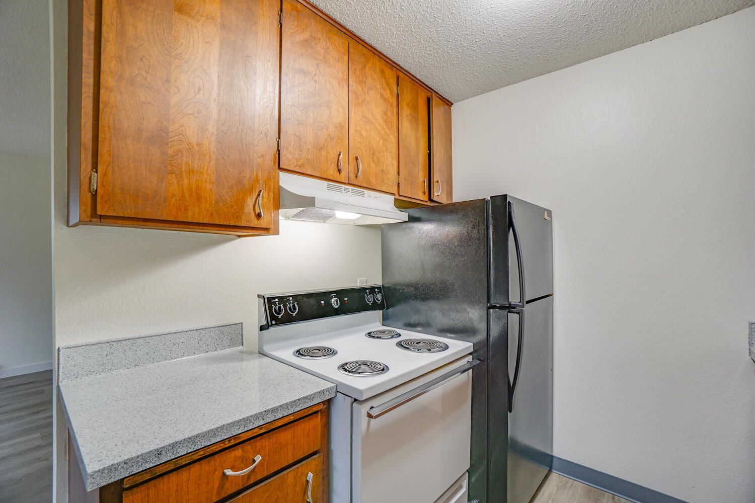 A kitchen with a stove , refrigerator , and wooden cabinets.