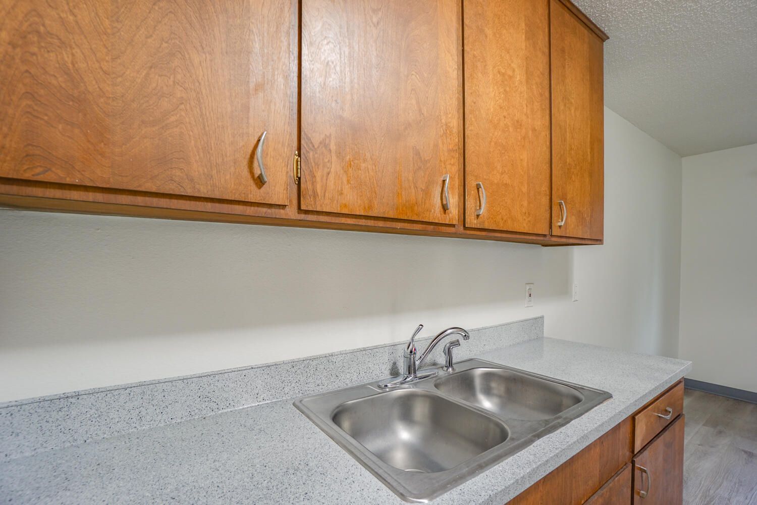 A kitchen with two sinks and wooden cabinets.