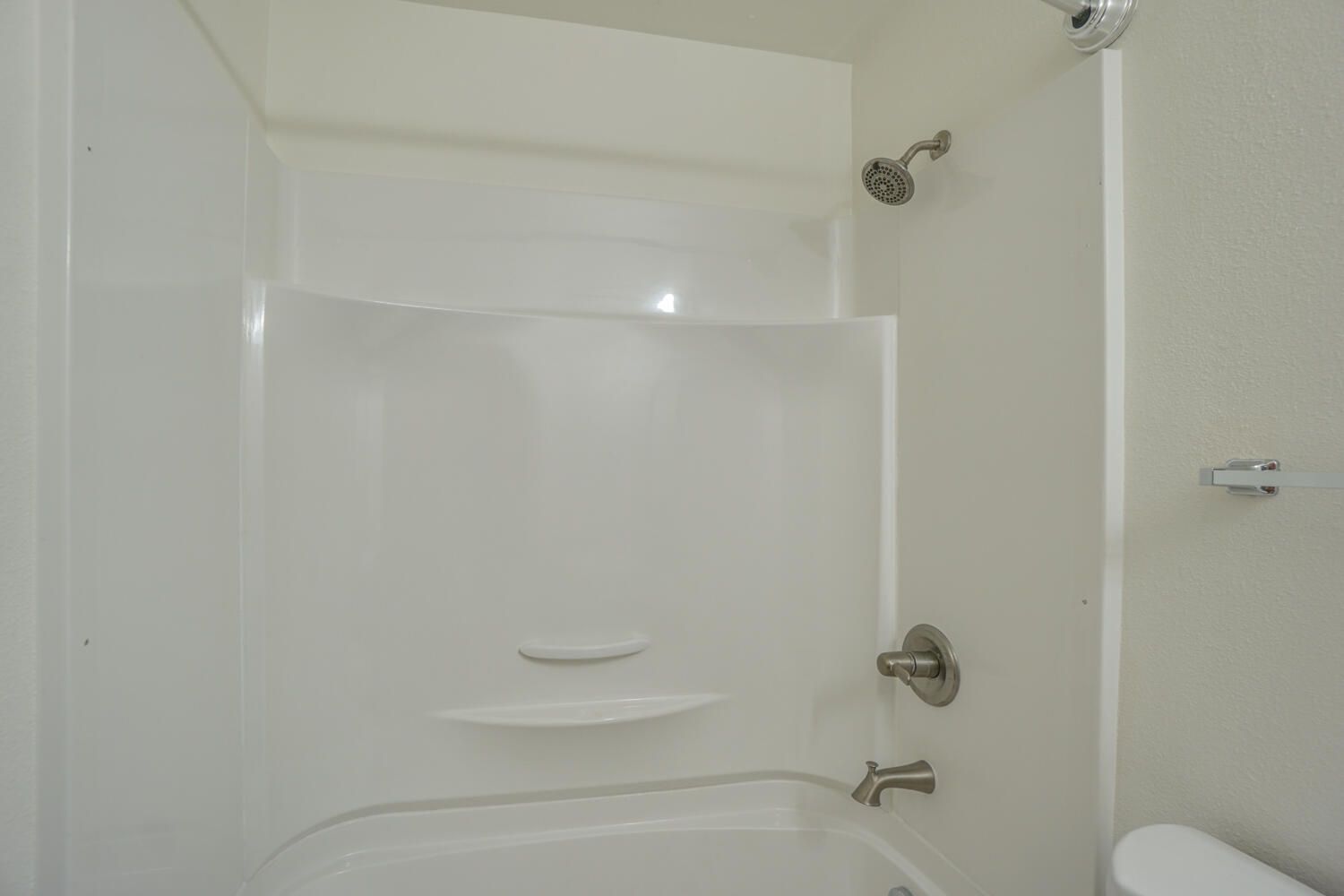 A bathroom with a tub , shower and toilet.