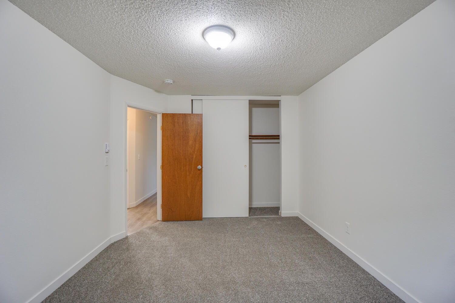 An empty bedroom with a closet and a door.
