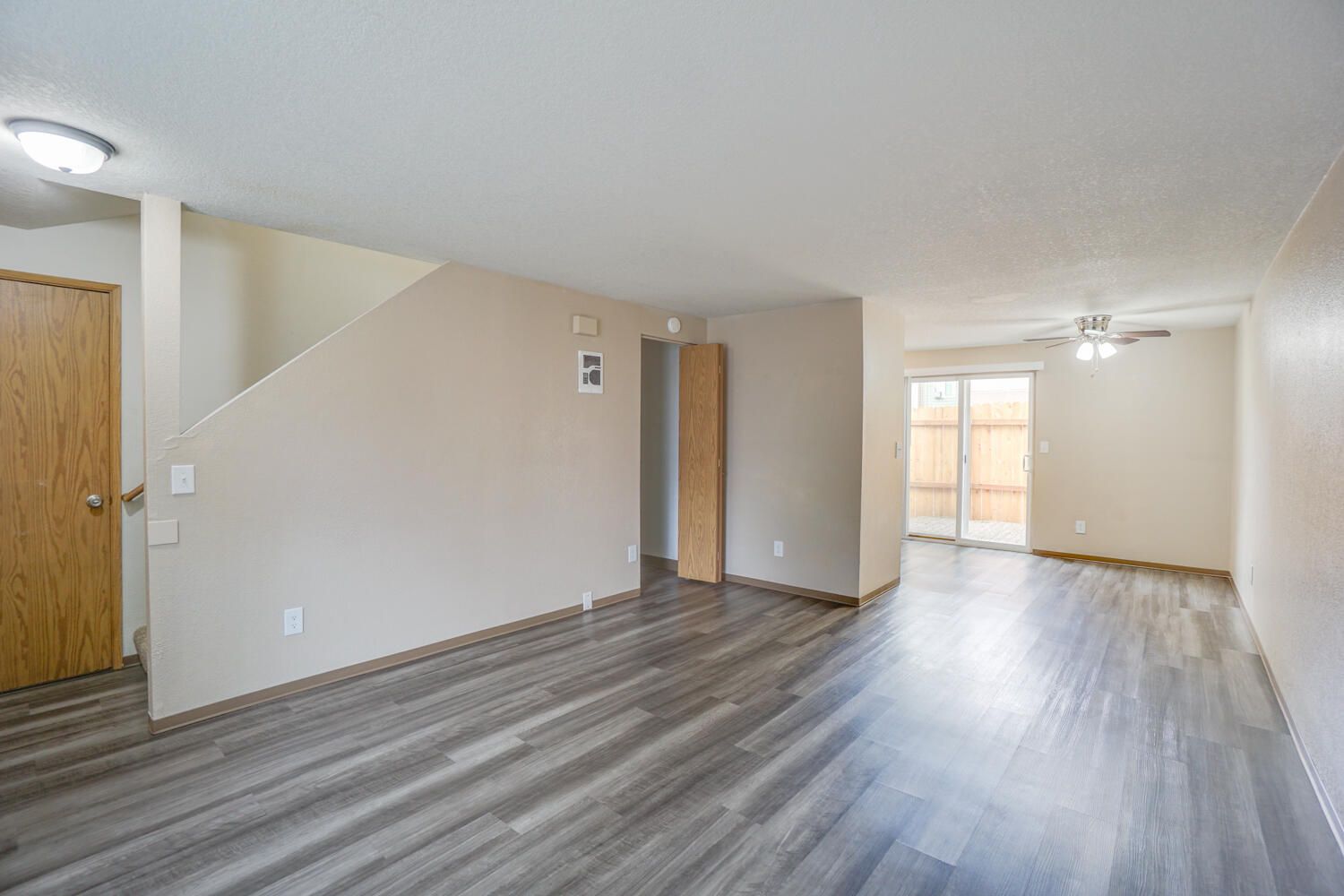 An empty living room with hardwood floors and a ceiling fan.