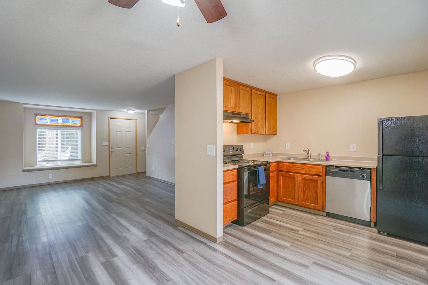 A kitchen with a stove , refrigerator , dishwasher , sink and ceiling fan.