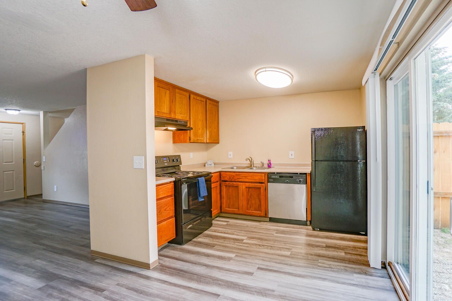 A kitchen with a refrigerator , stove , dishwasher and sliding glass doors.