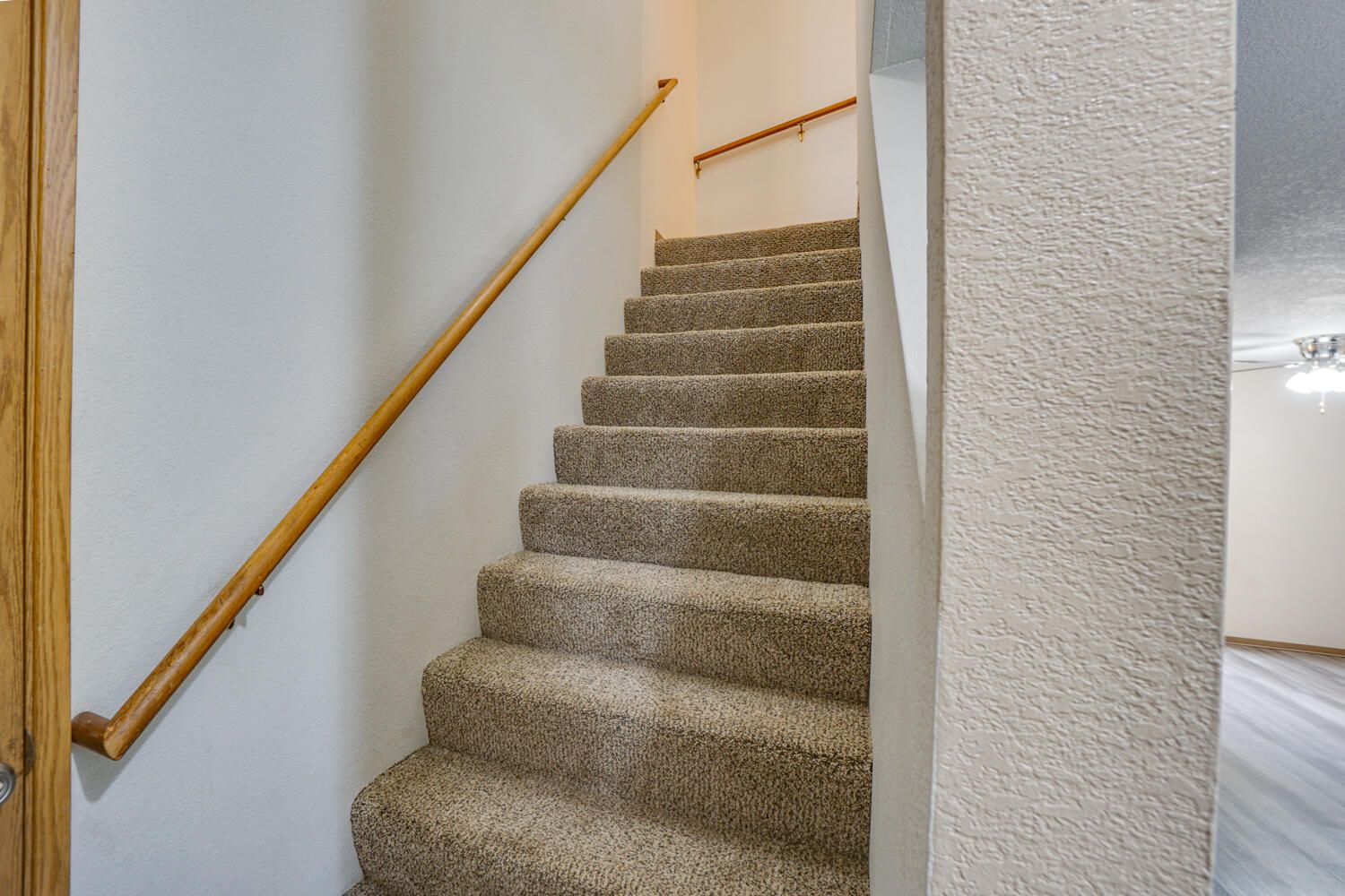 The stairs are carpeted and have a wooden railing.