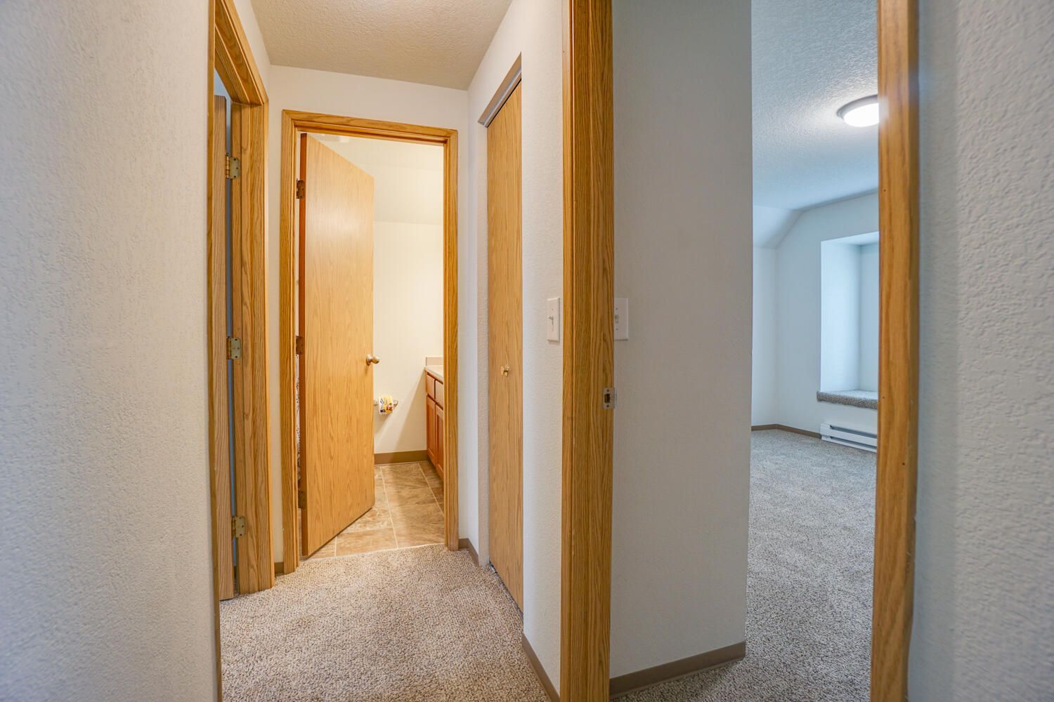 A hallway leading to a bathroom and a bedroom in a house.