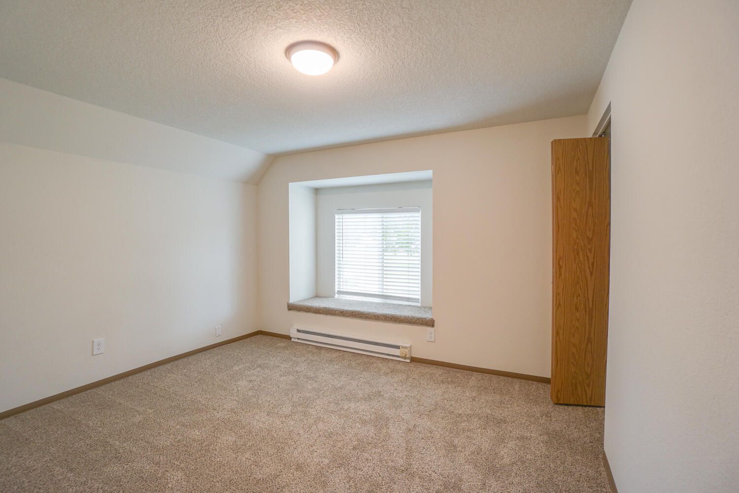 An empty bedroom with a window and a light on the ceiling.