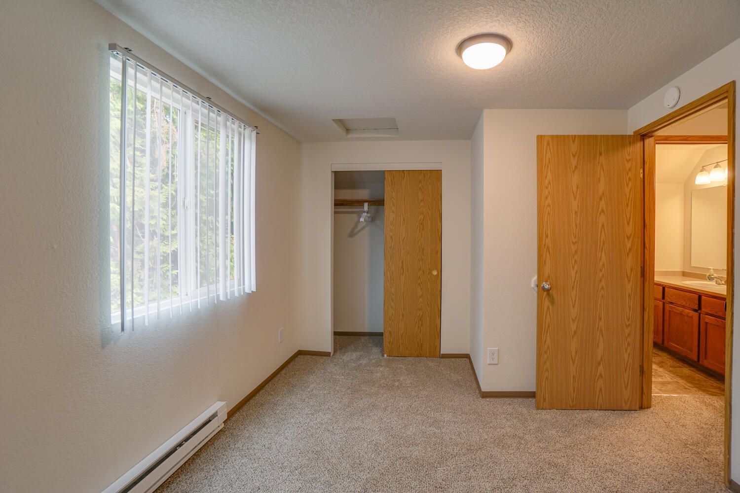 An empty bedroom with a closet and a window.