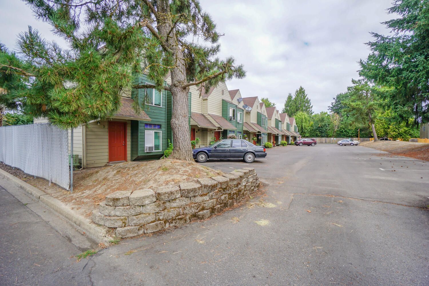 A car is parked in front of a row of apartment buildings.
