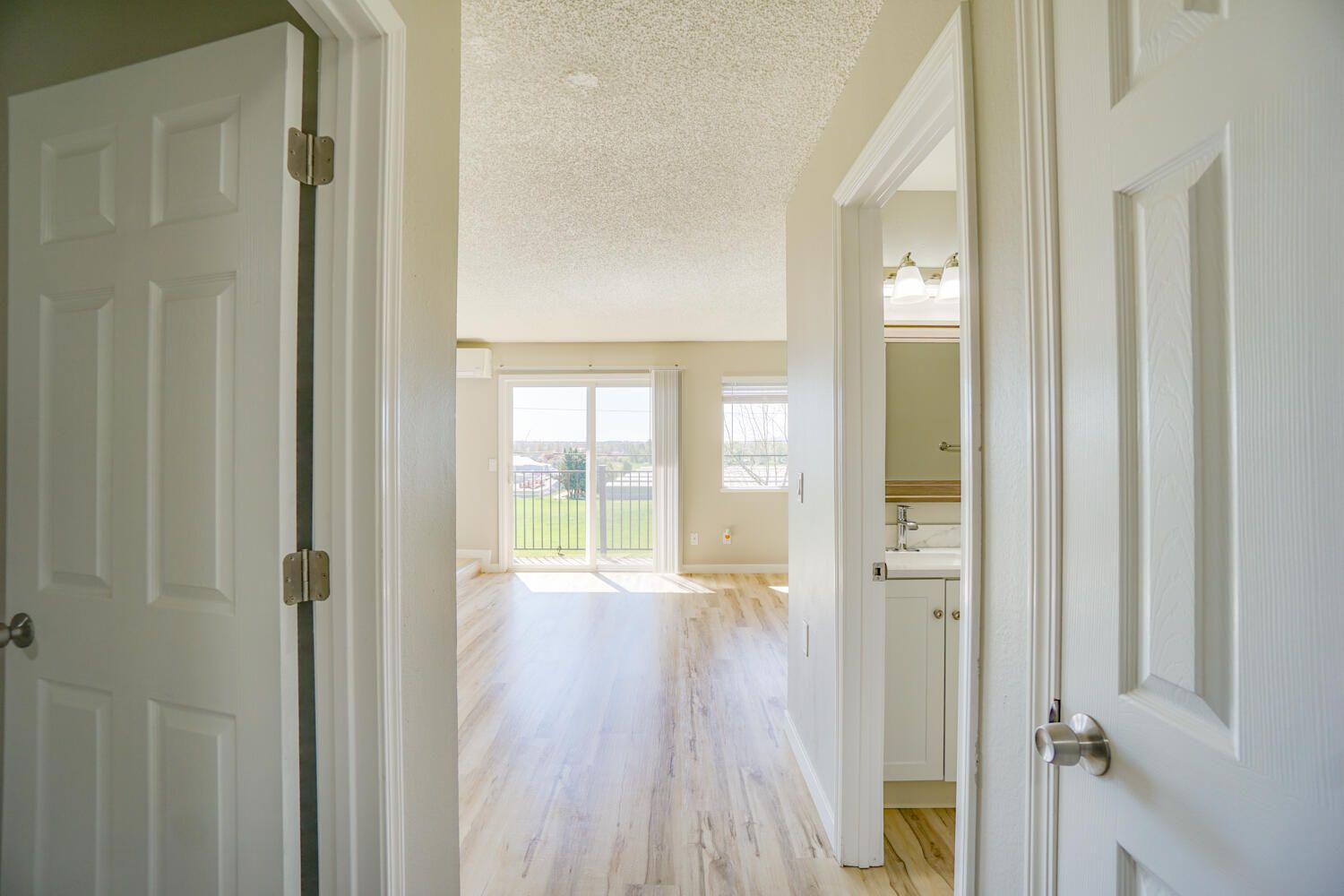 A hallway leading to a living room and a bathroom in a house.