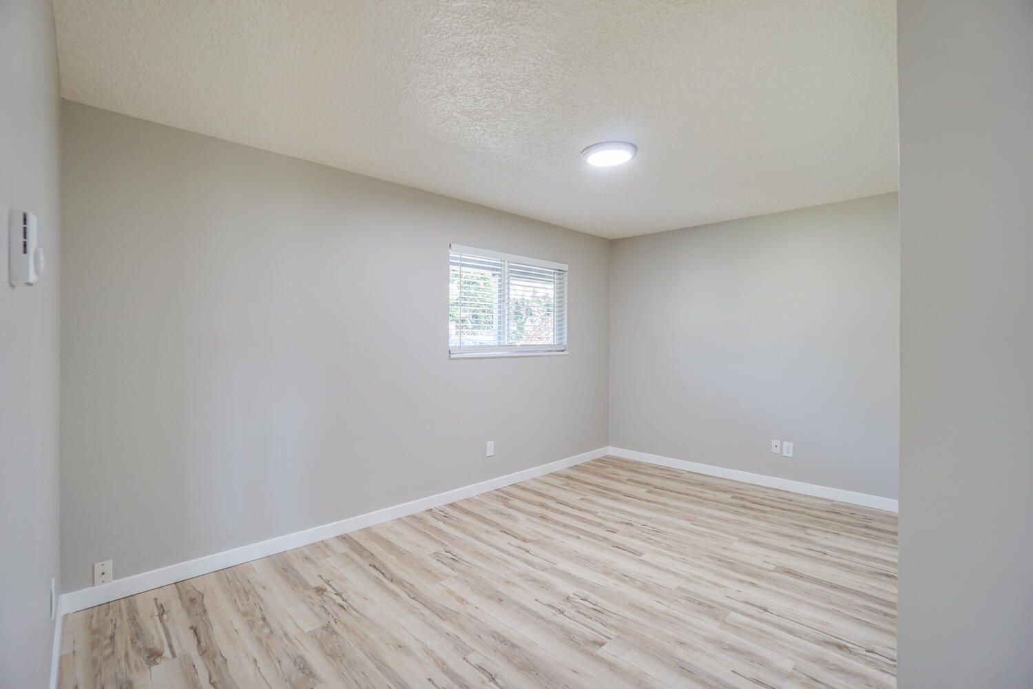 An empty room with hardwood floors and a window.