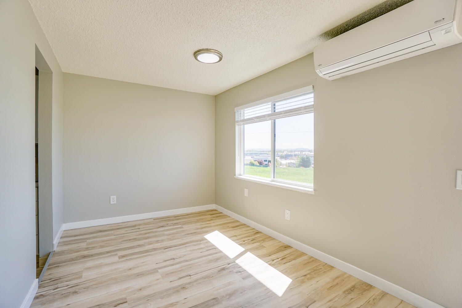 An empty room with hardwood floors and a window.