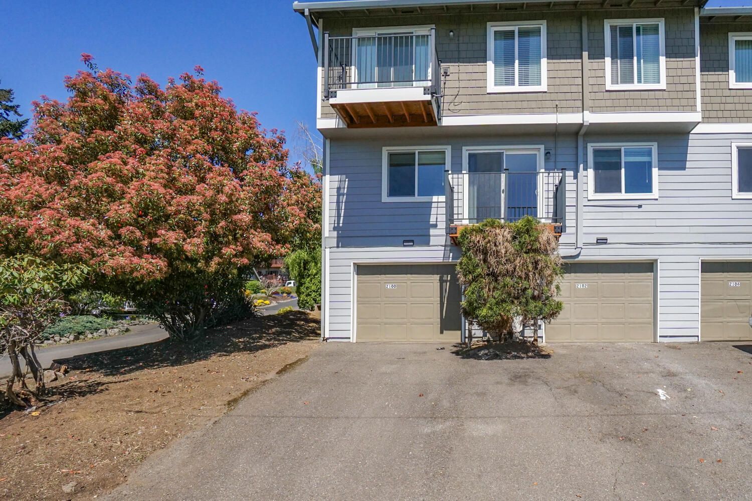 A house with two garages and a tree in front of it.
