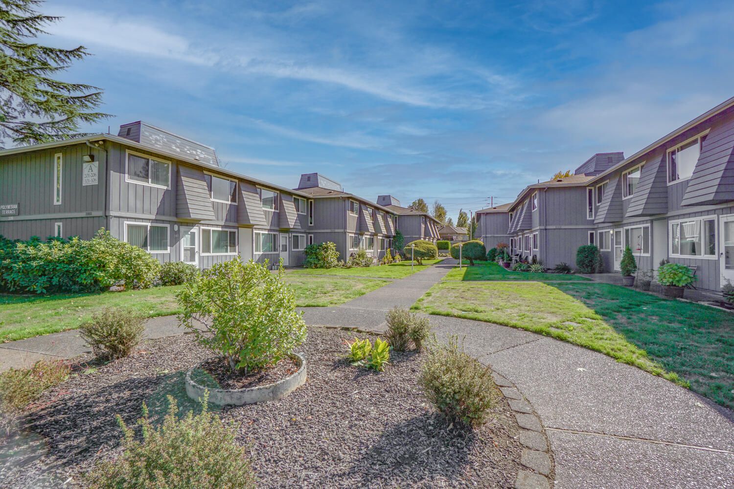 A row of apartment buildings with a walkway between them.