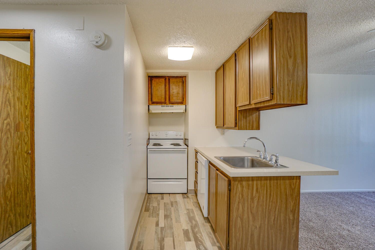 A kitchen with wooden cabinets , a sink , and a stove.