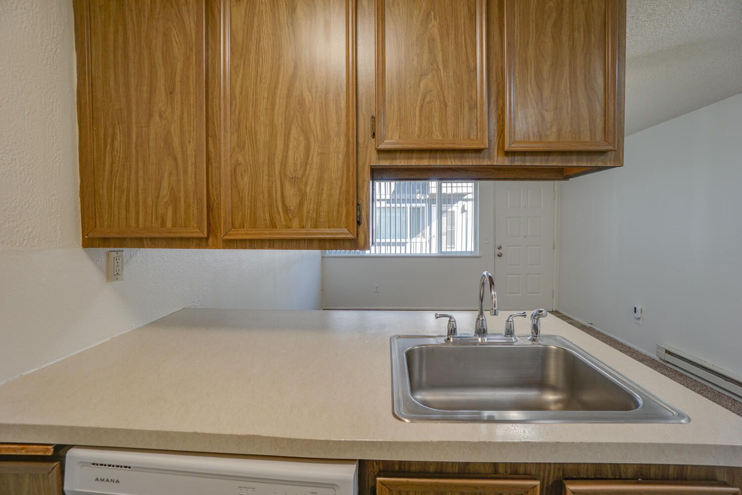 A kitchen with a sink , dishwasher , and wooden cabinets.