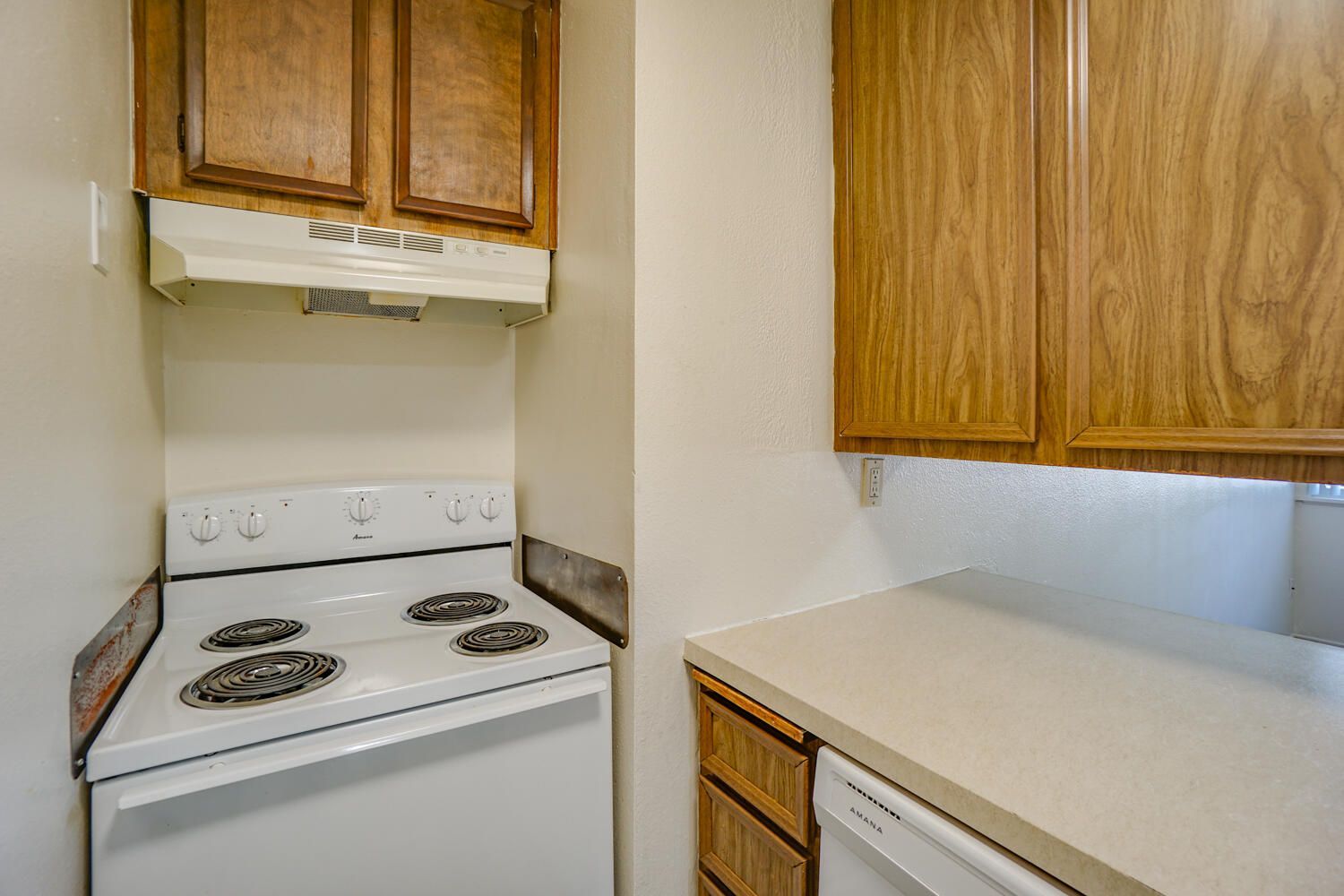A kitchen with a stove , dishwasher , and cabinets.