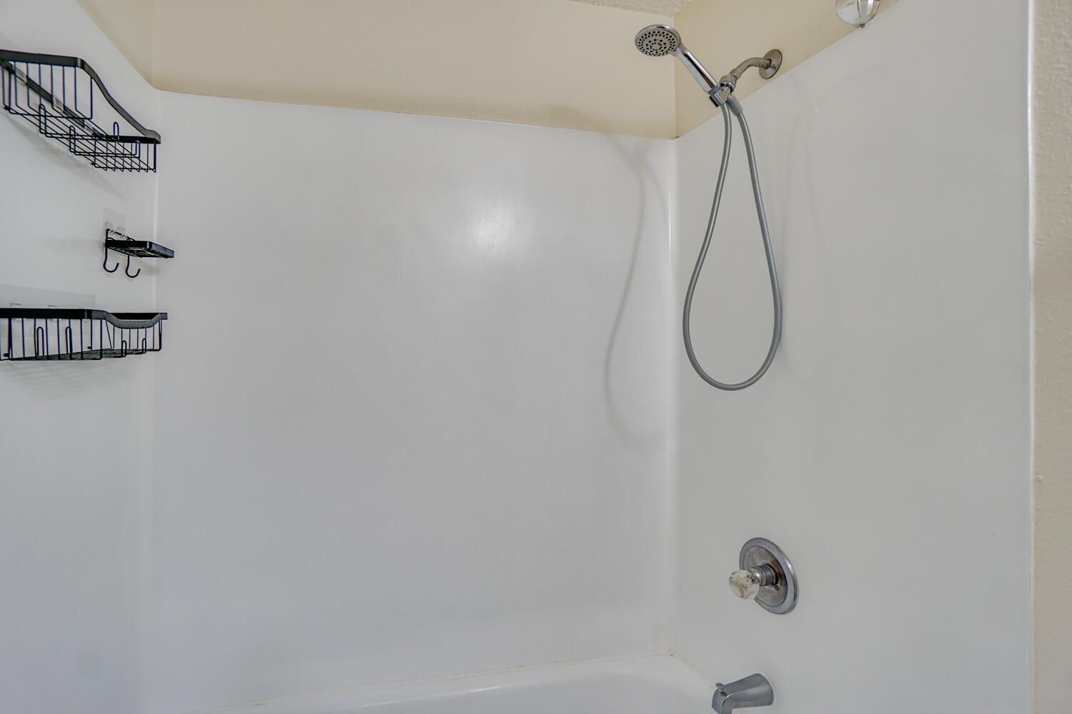 A bathroom with a bathtub and a shower head.