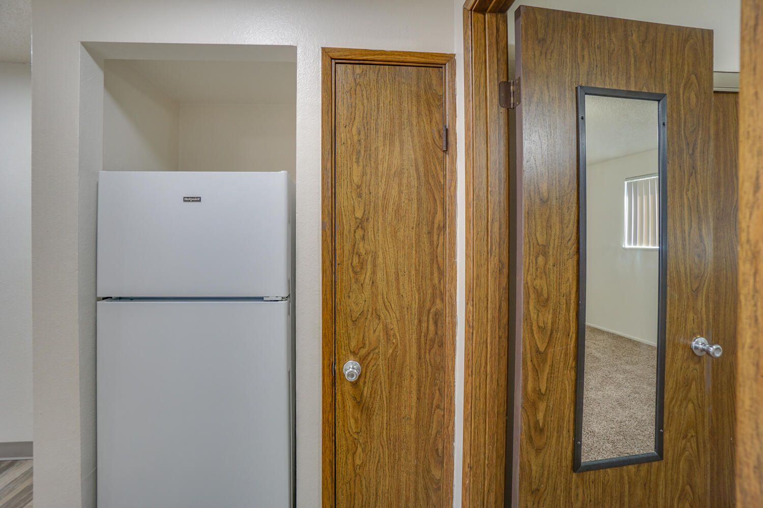 There is a refrigerator and a mirror in the room.