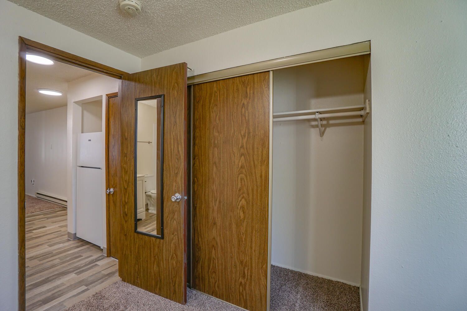 A bedroom with a closet and a refrigerator.