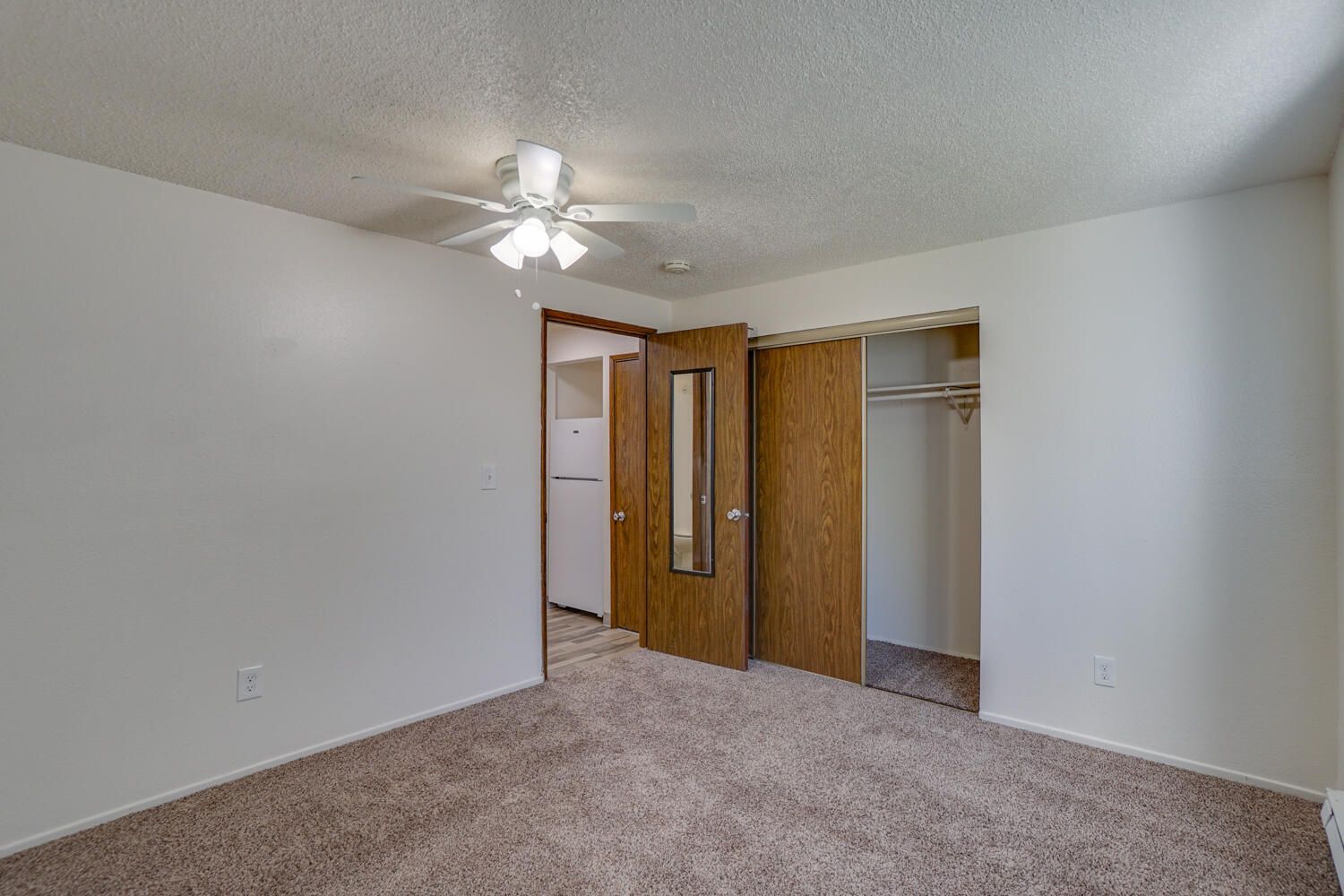 An empty bedroom with a ceiling fan and a closet.