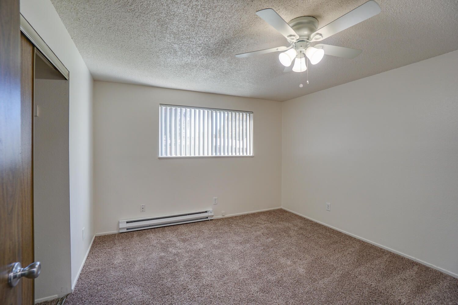 An empty bedroom with a ceiling fan and a window.
