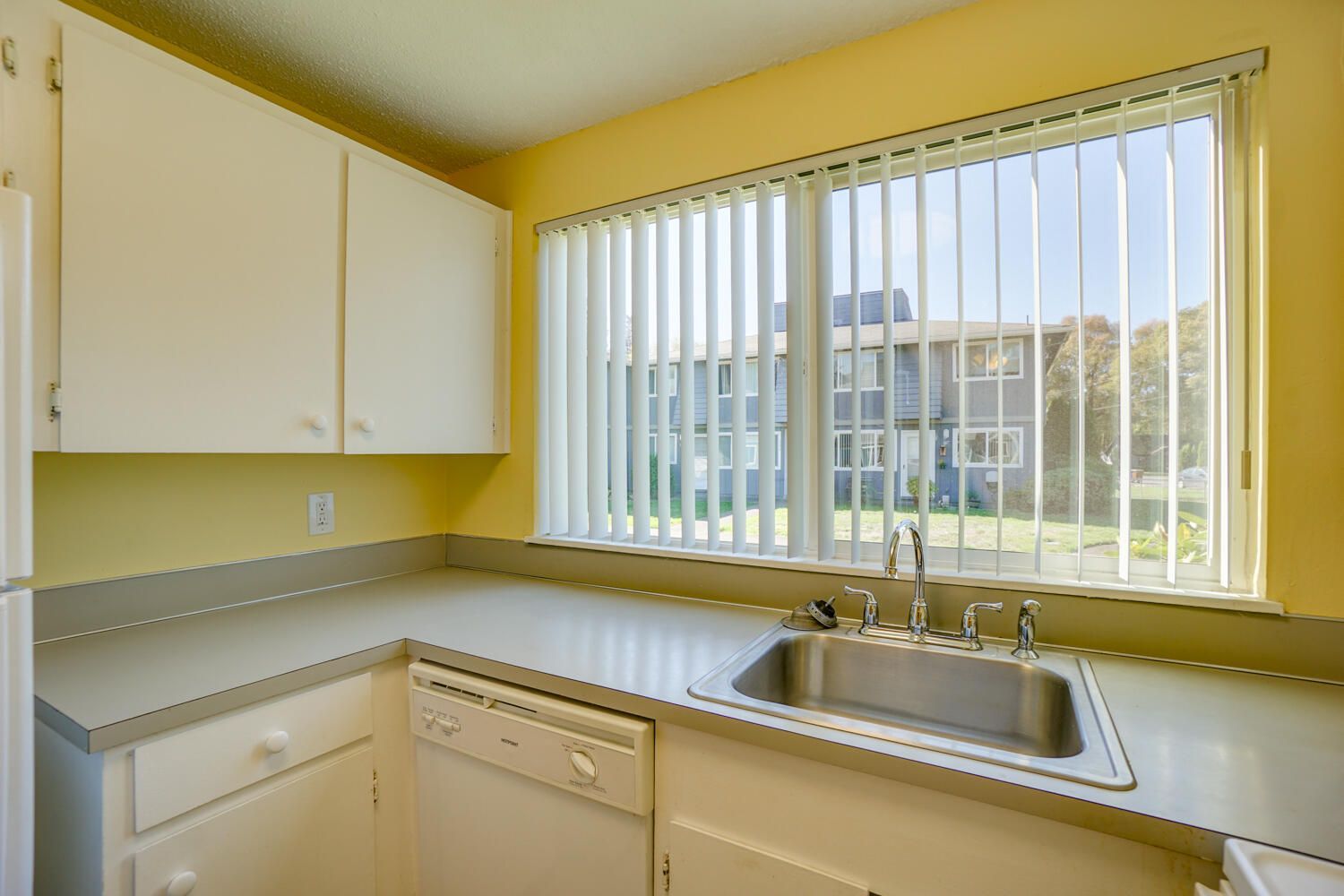 A kitchen with a sink and a window with blinds