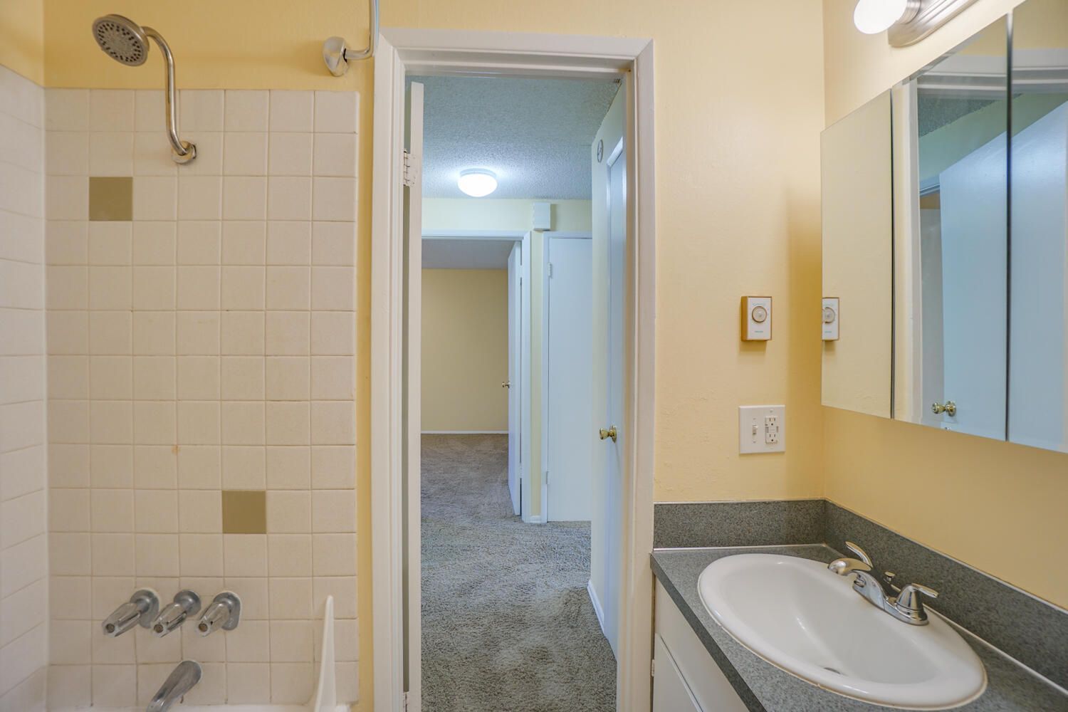 A bathroom with a sink , shower and mirror.