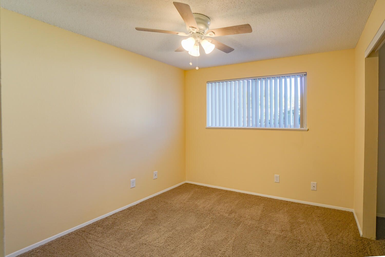 An empty bedroom with a ceiling fan and a window.