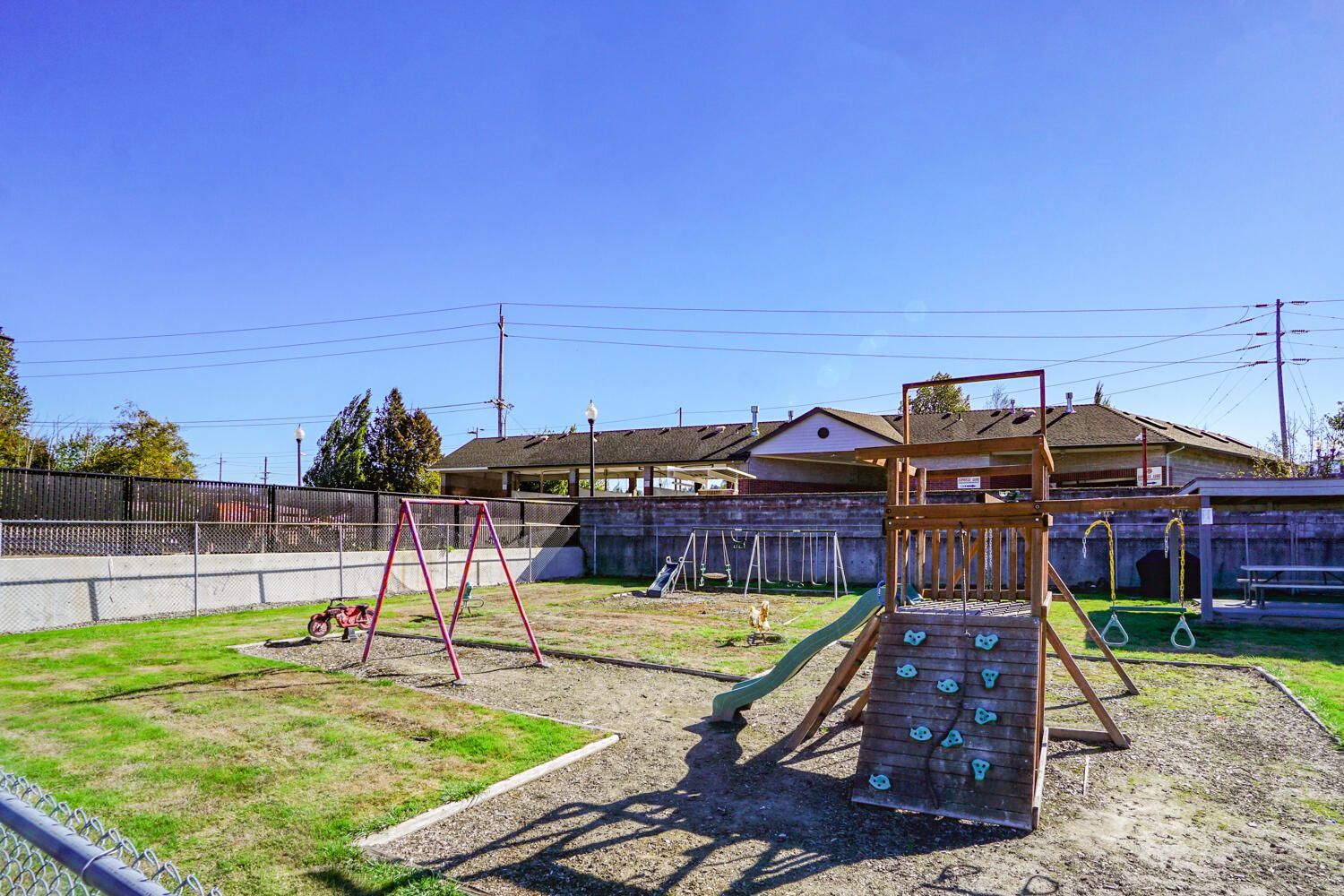 A playground with a slide , swings , and a climbing wall.
