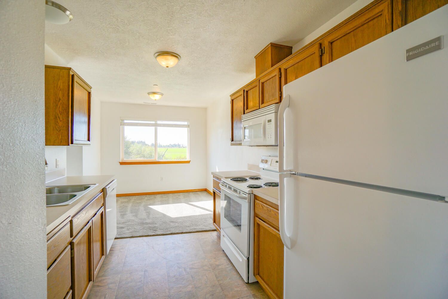 A kitchen with a refrigerator , stove , microwave and sink.