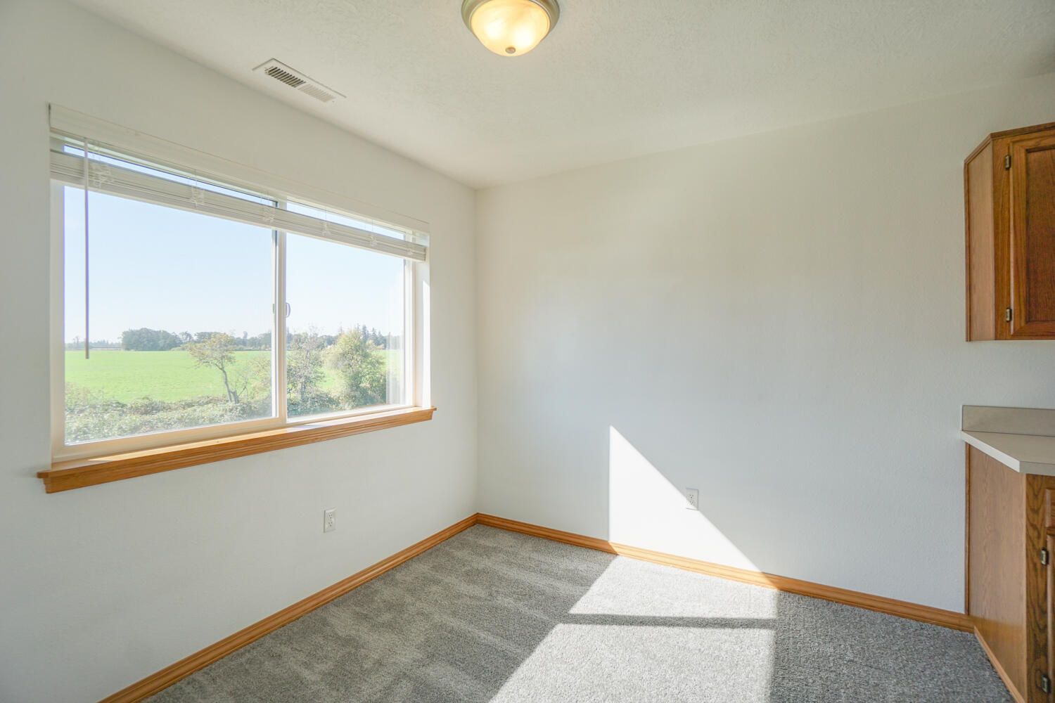 An empty room with a large window and a view of a field.