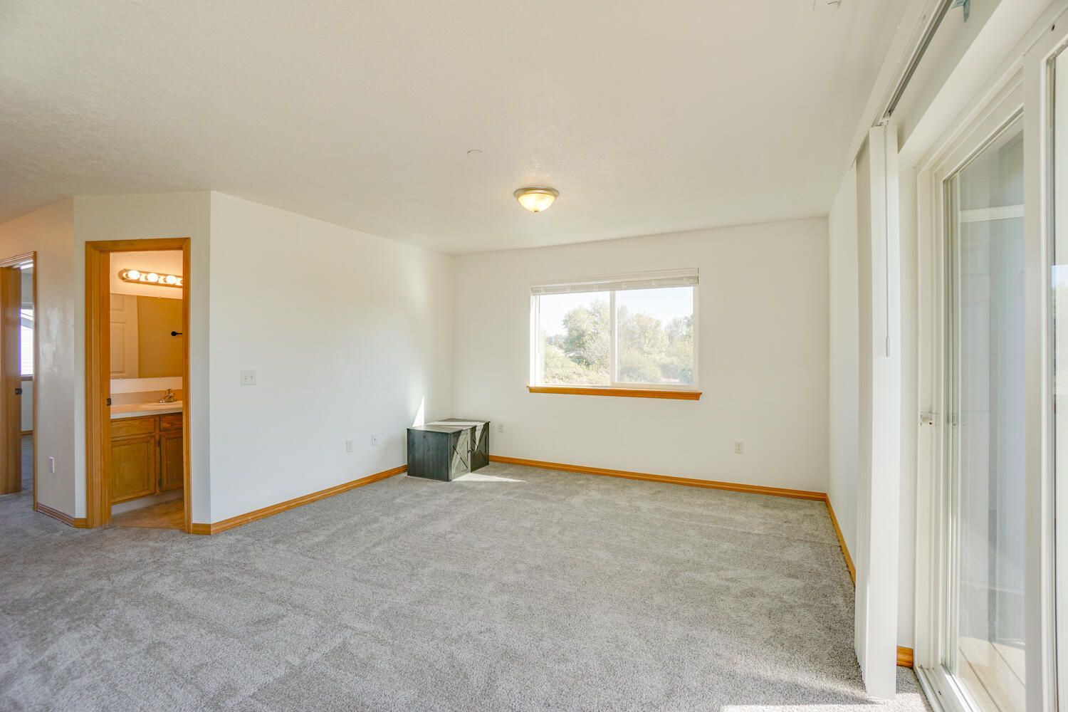 An empty living room with a sliding glass door and a window
