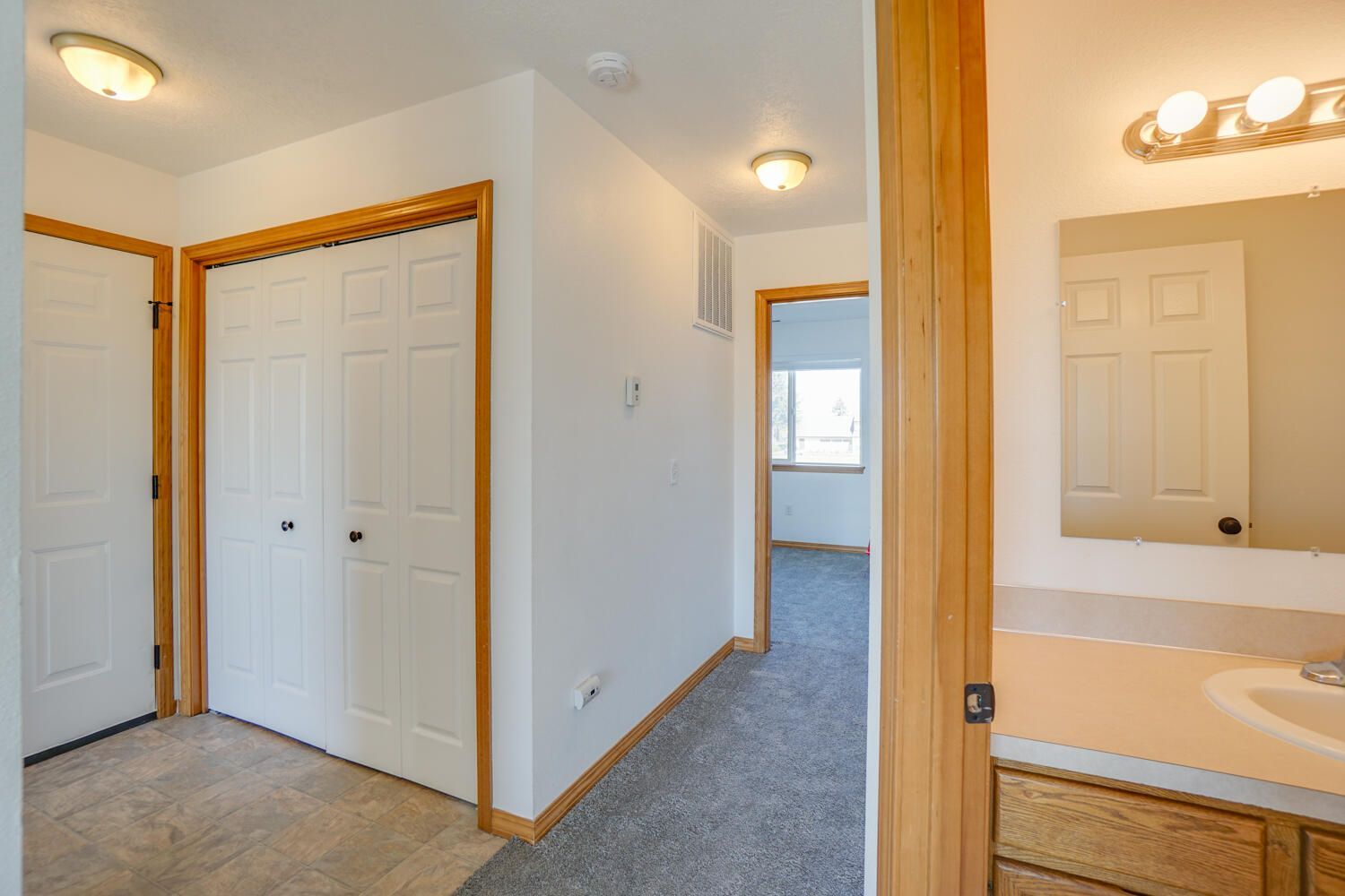 A hallway leading to a bathroom and a bedroom in a house.