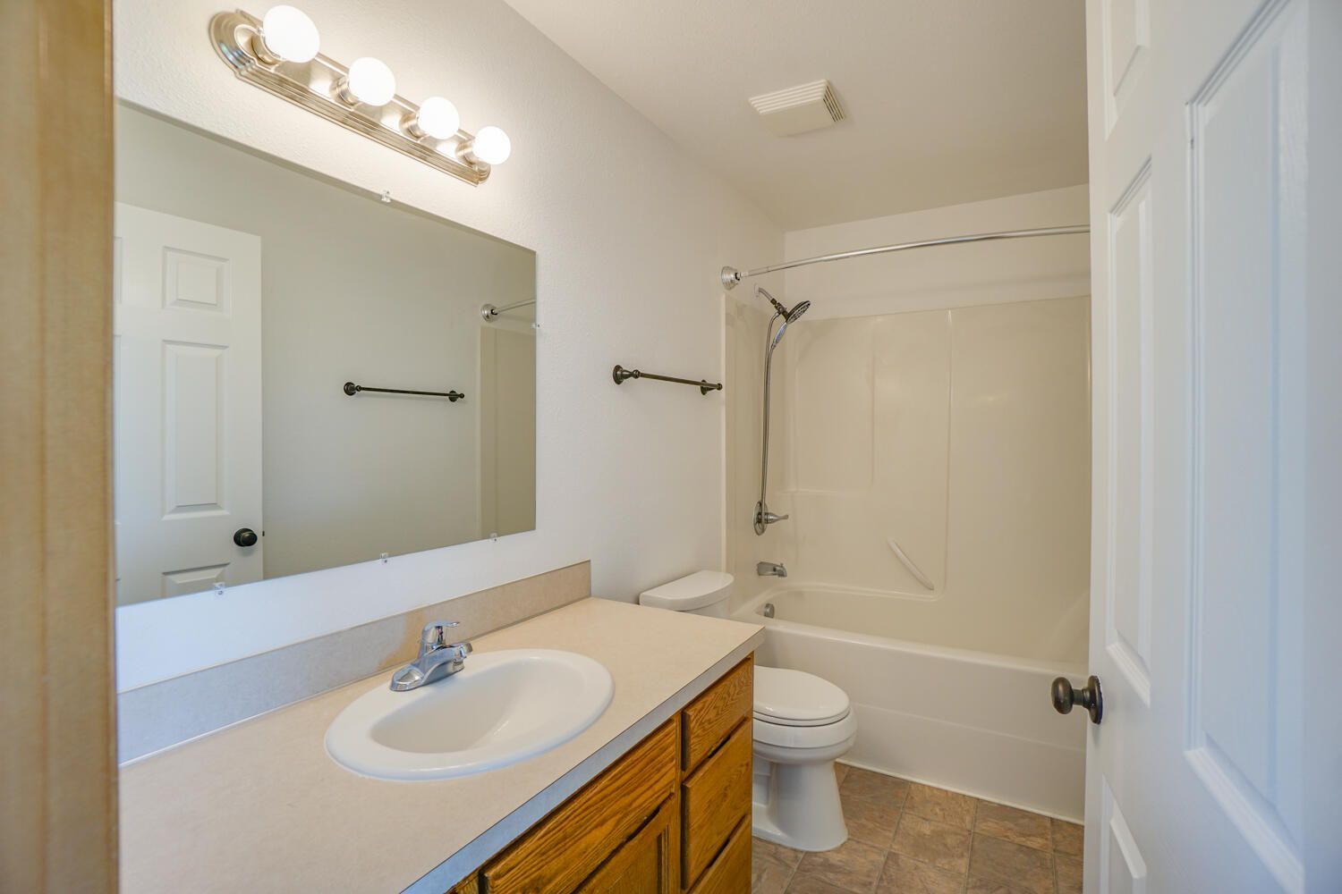 A bathroom with a sink , toilet , bathtub and mirror.