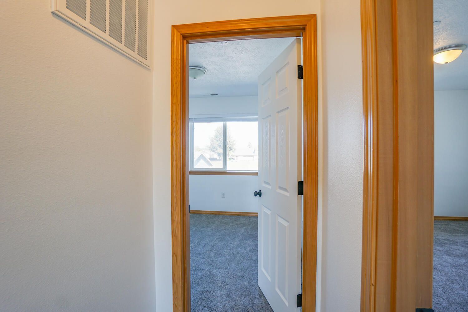 A hallway with a door open leading to a bedroom.
