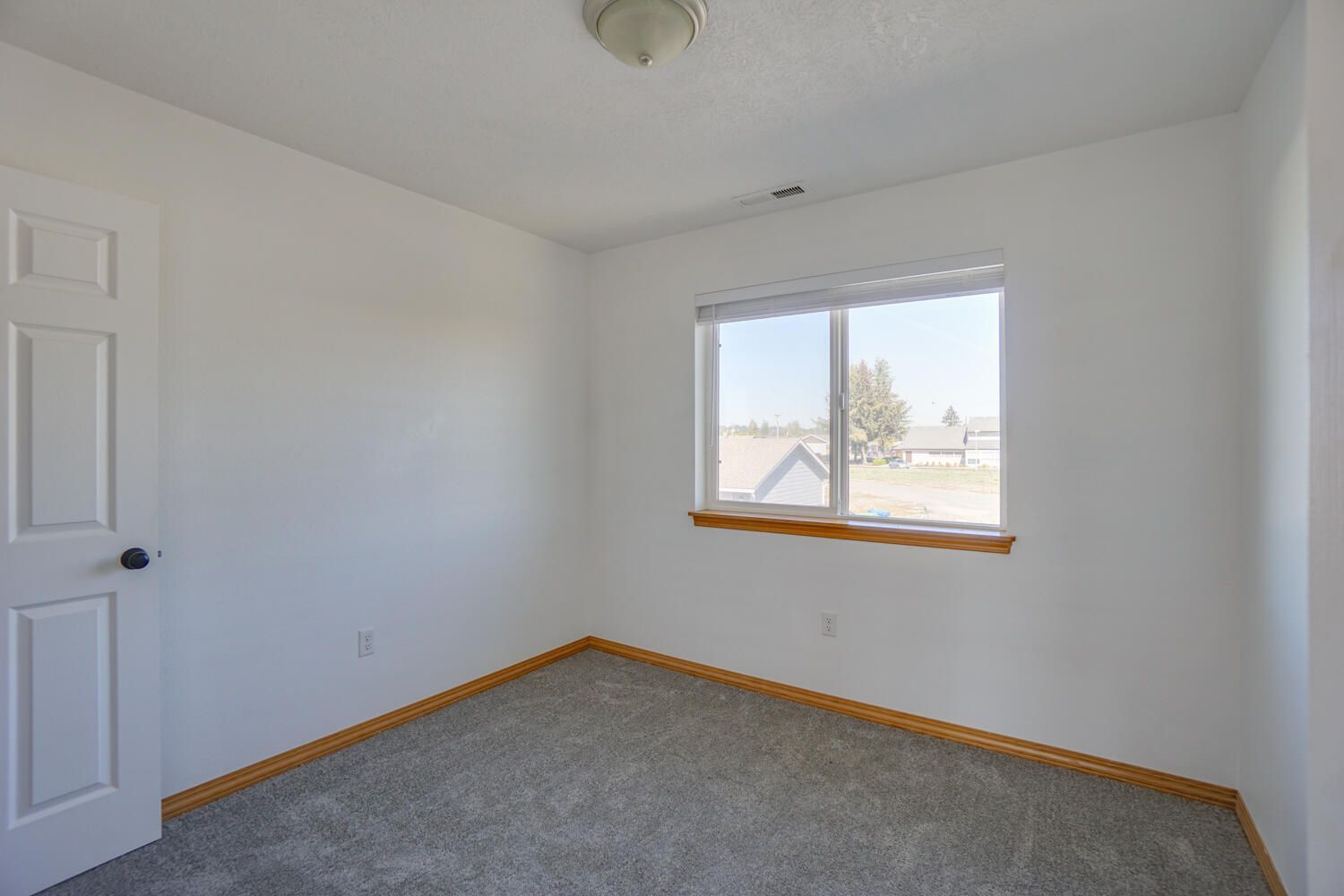 An empty bedroom with a window and carpet.