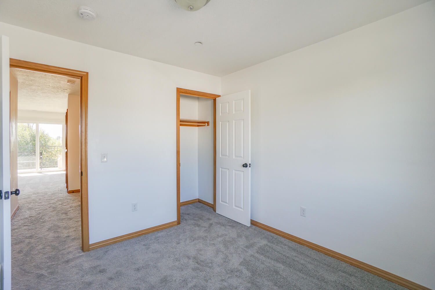 An empty bedroom with a closet and a window.