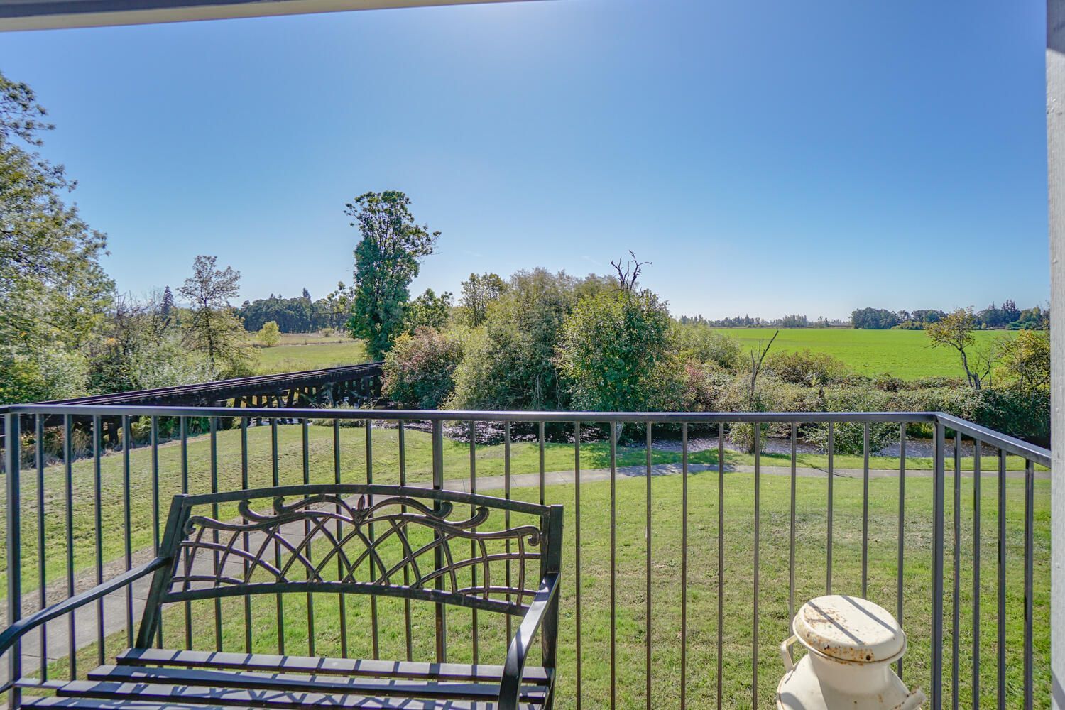 There is a bench on the balcony with a view of a field.