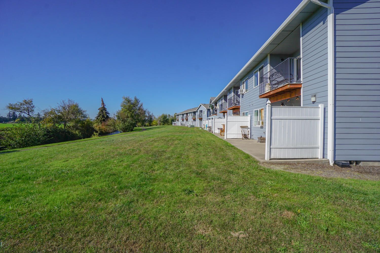 A row of apartment buildings with a lush green lawn in front of them.