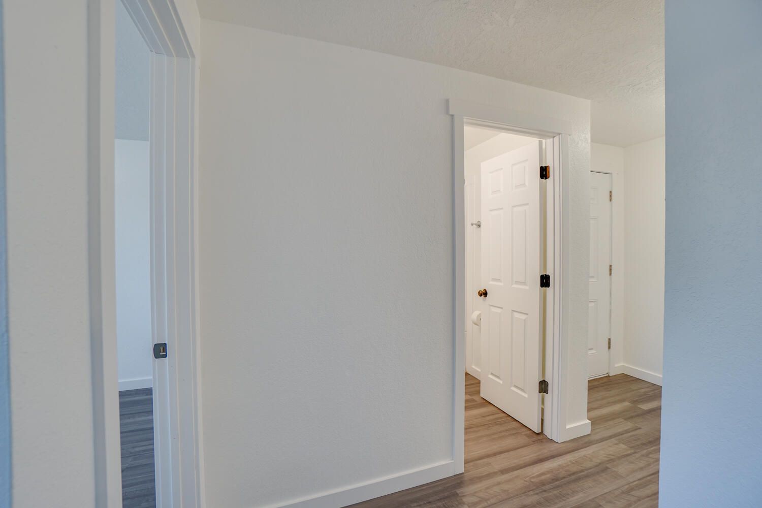A hallway leading to a bedroom and a bathroom in a house.