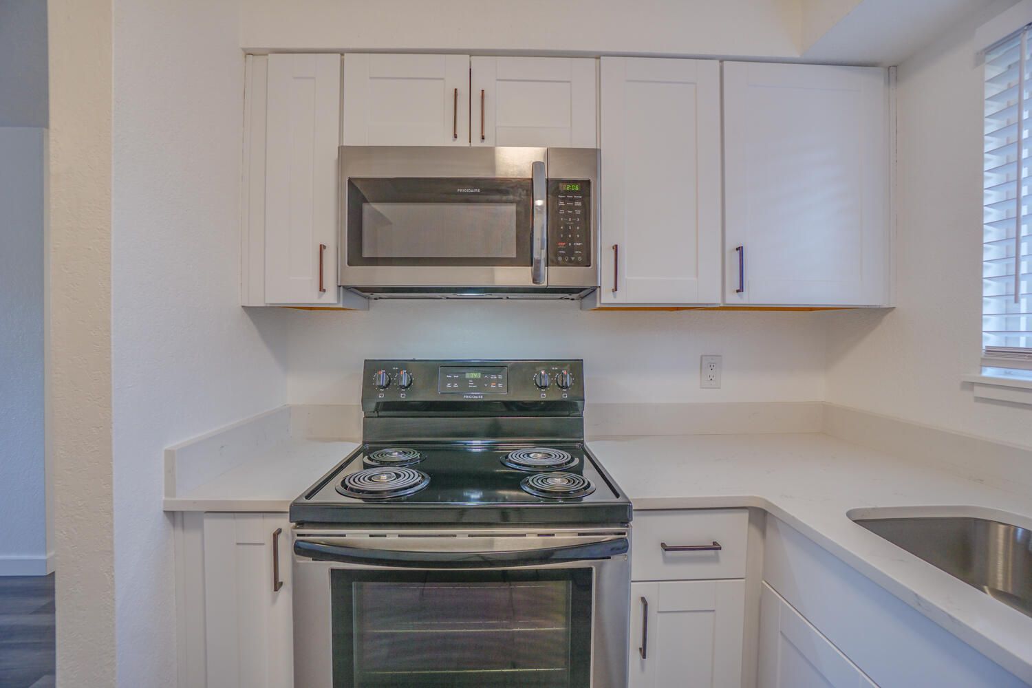 A kitchen with white cabinets and a stove and microwave