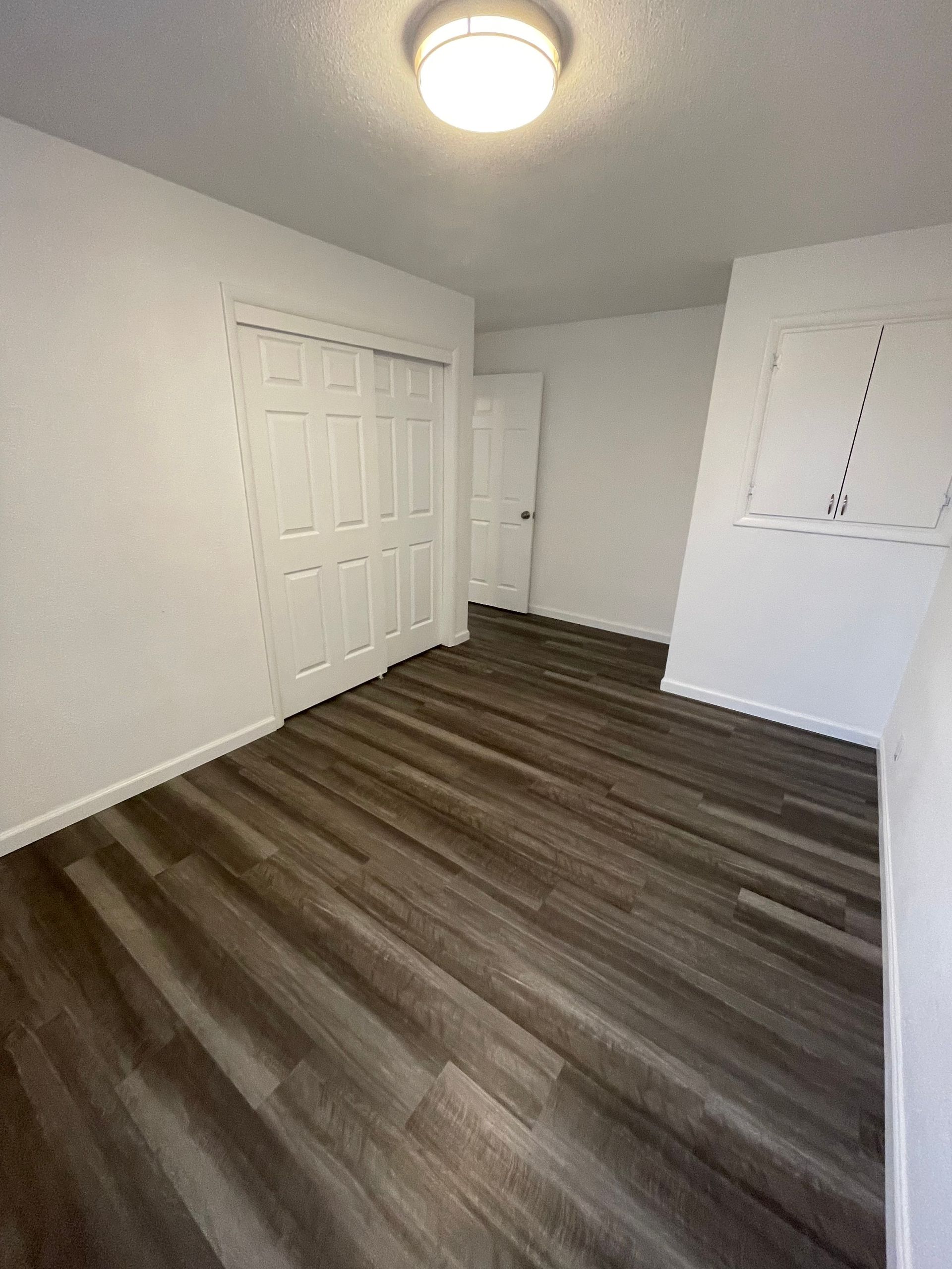 A bedroom with hardwood floors and a closet.