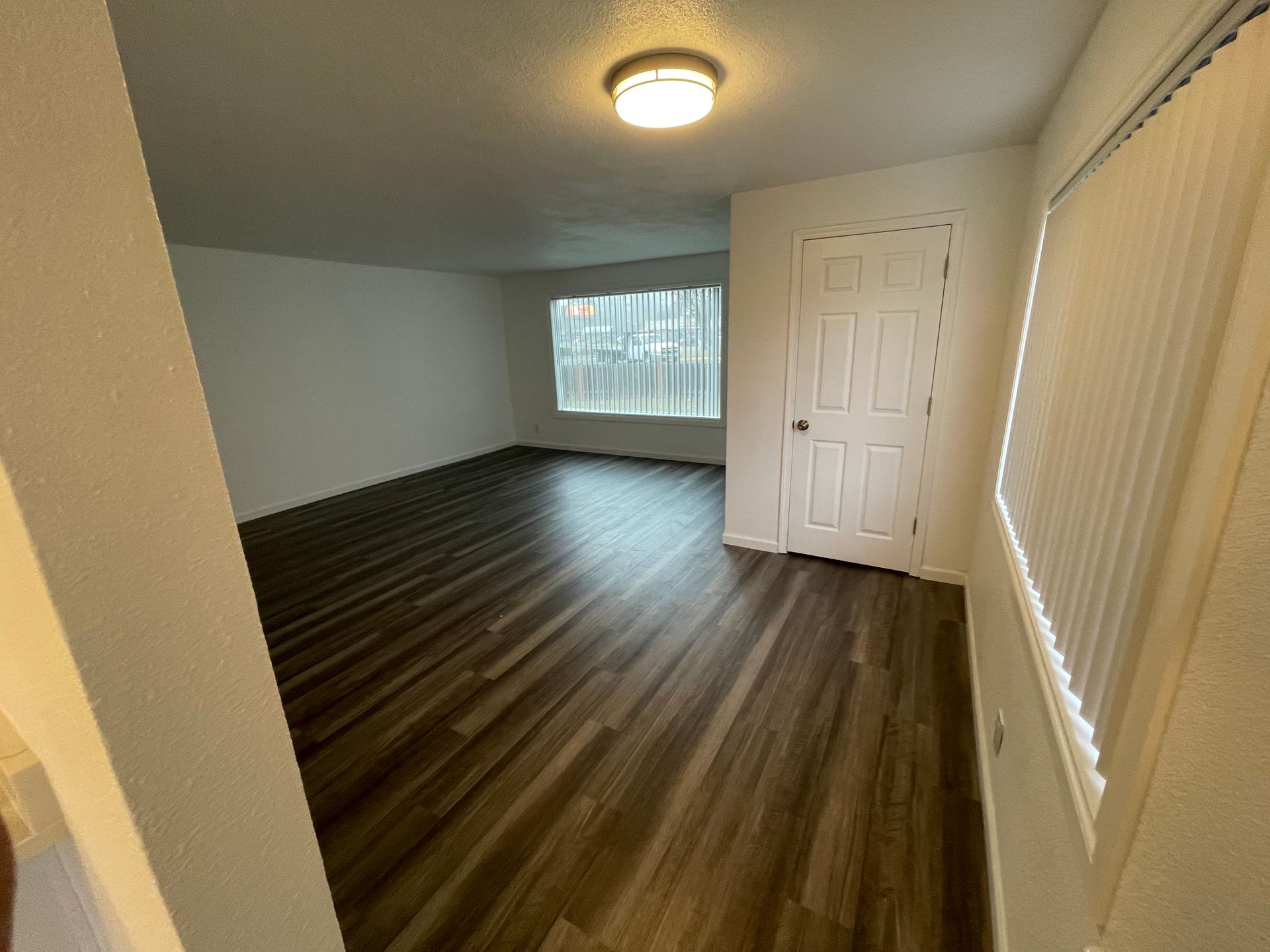 An empty living room with hardwood floors and a window.