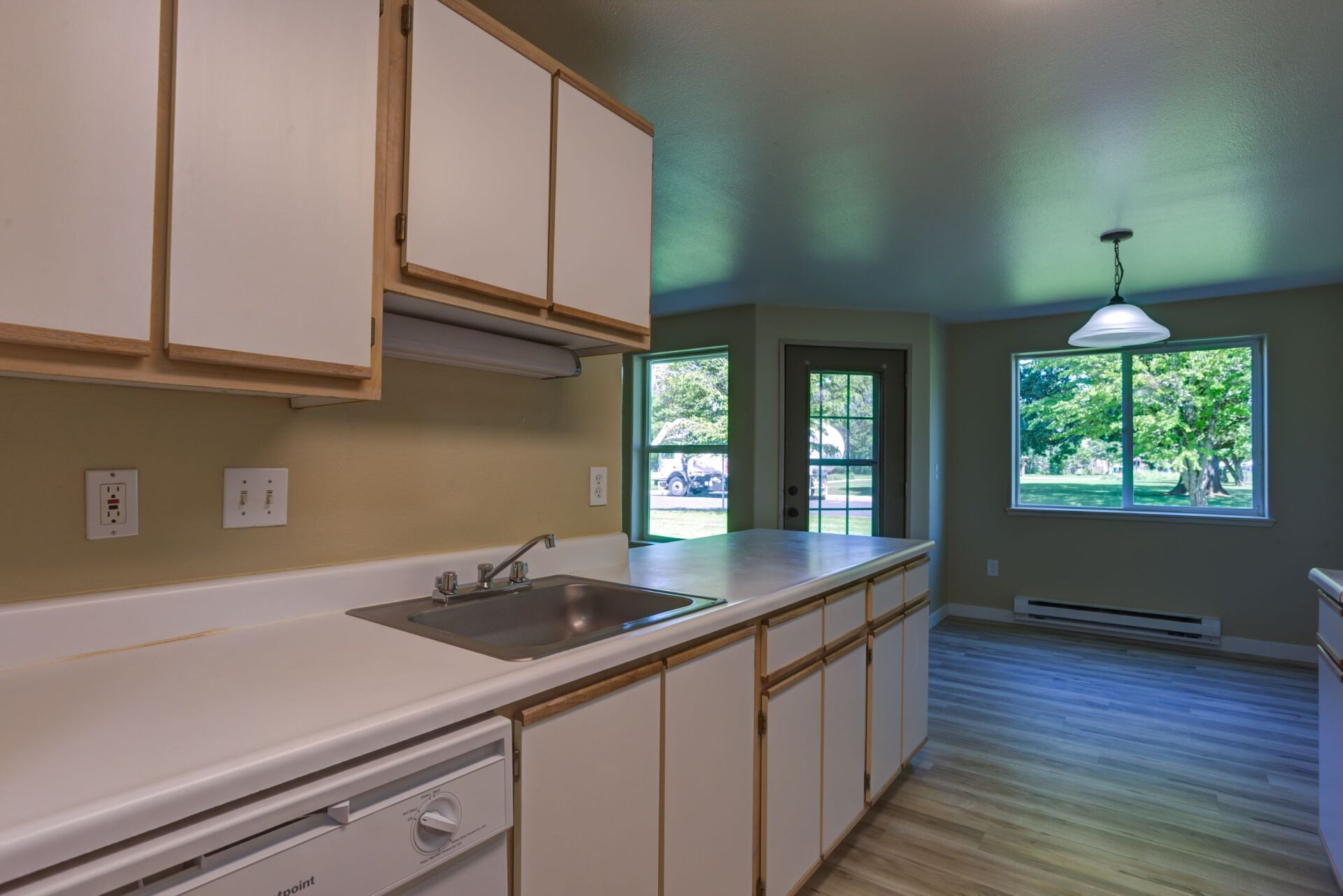 A kitchen with white cabinets , a sink , and a dishwasher.