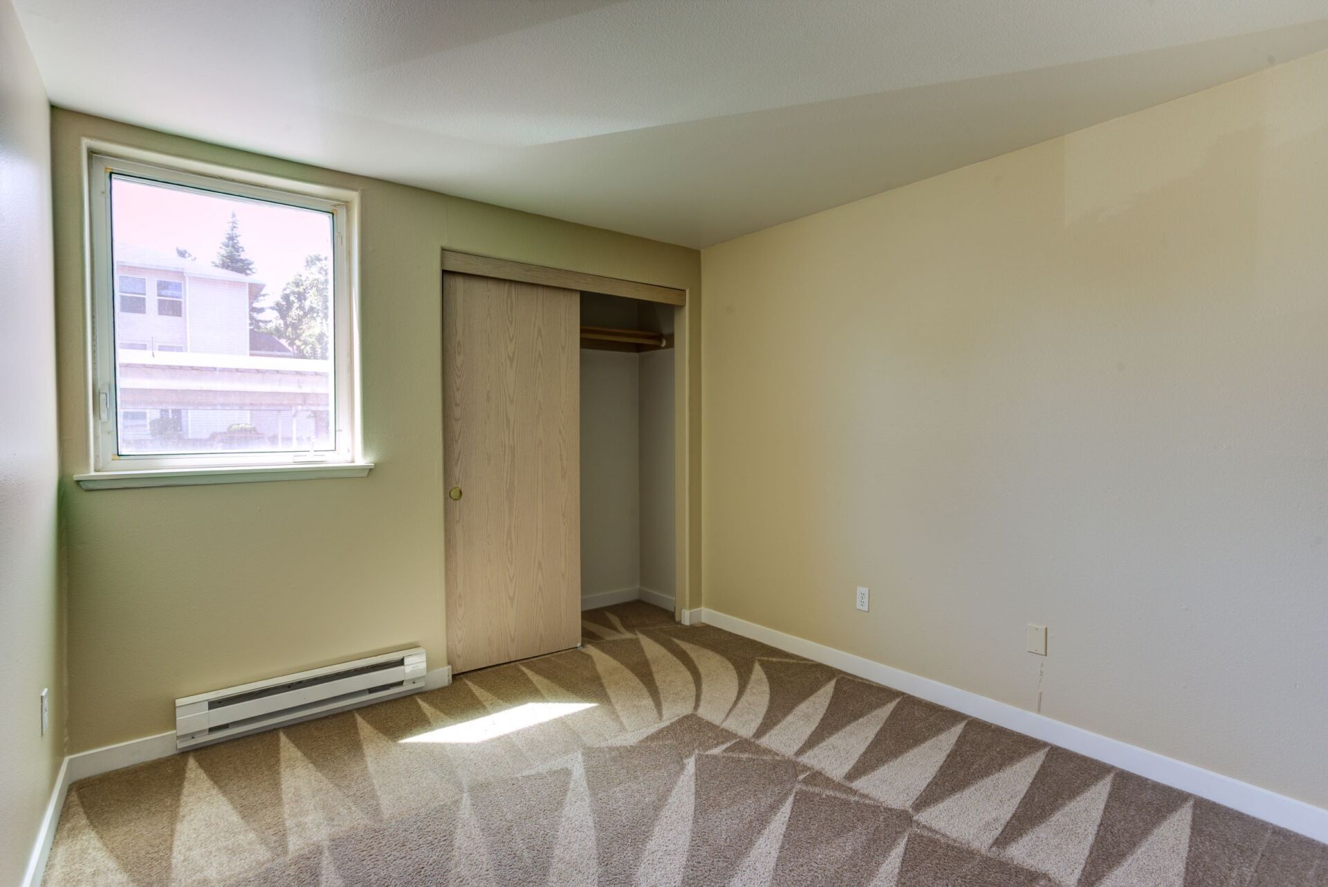 An empty bedroom with a sliding glass door and a window.