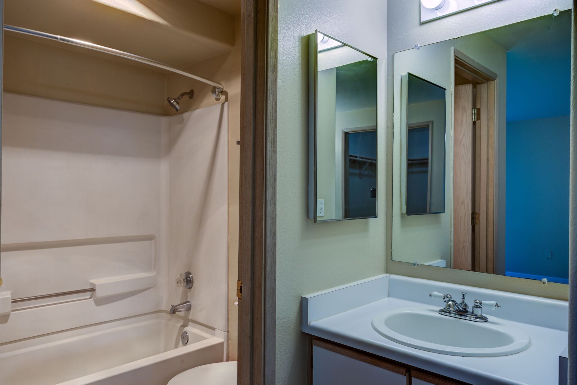 A bathroom with a sink , toilet , shower and mirror.