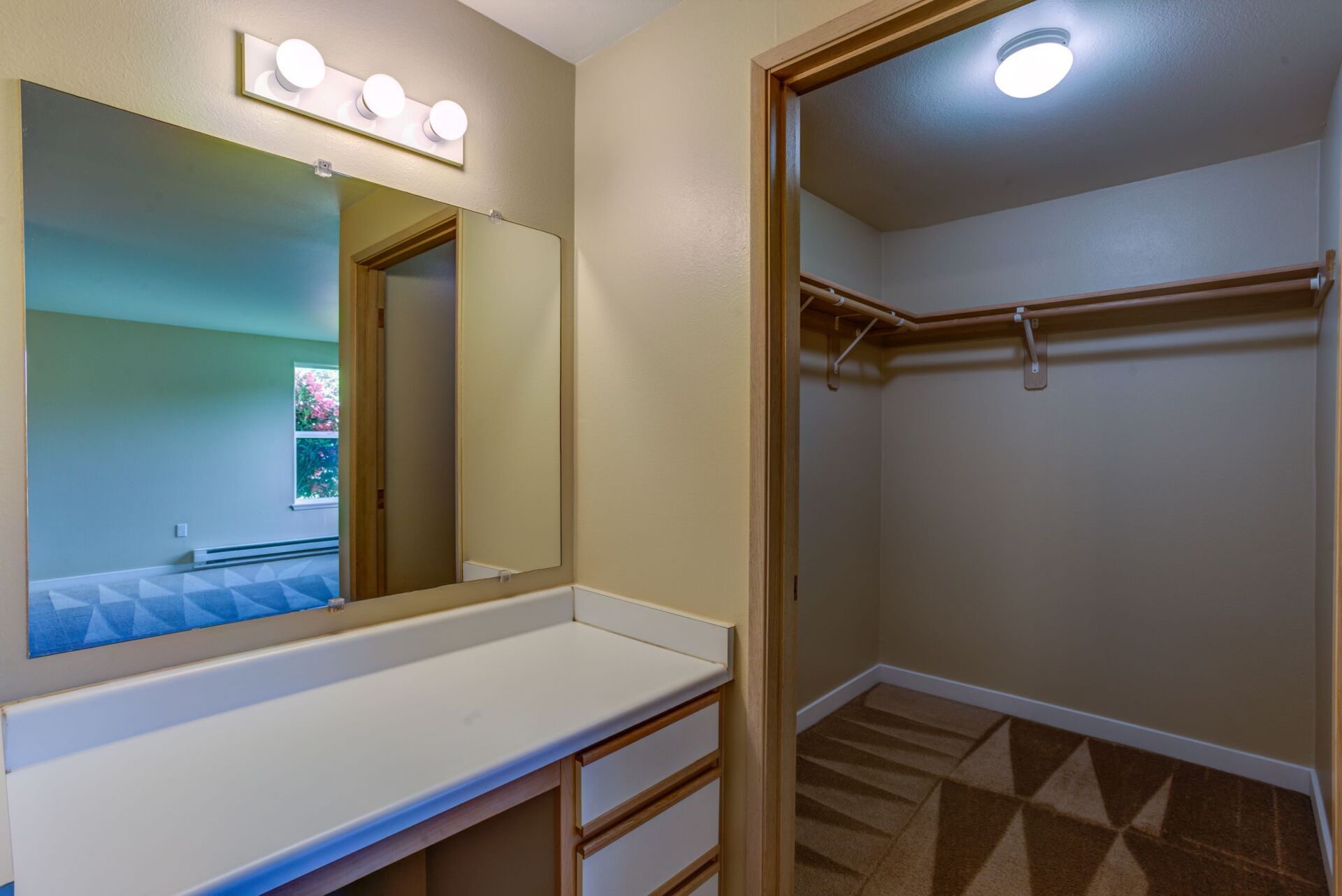 A walk in closet with a vanity and a large mirror.