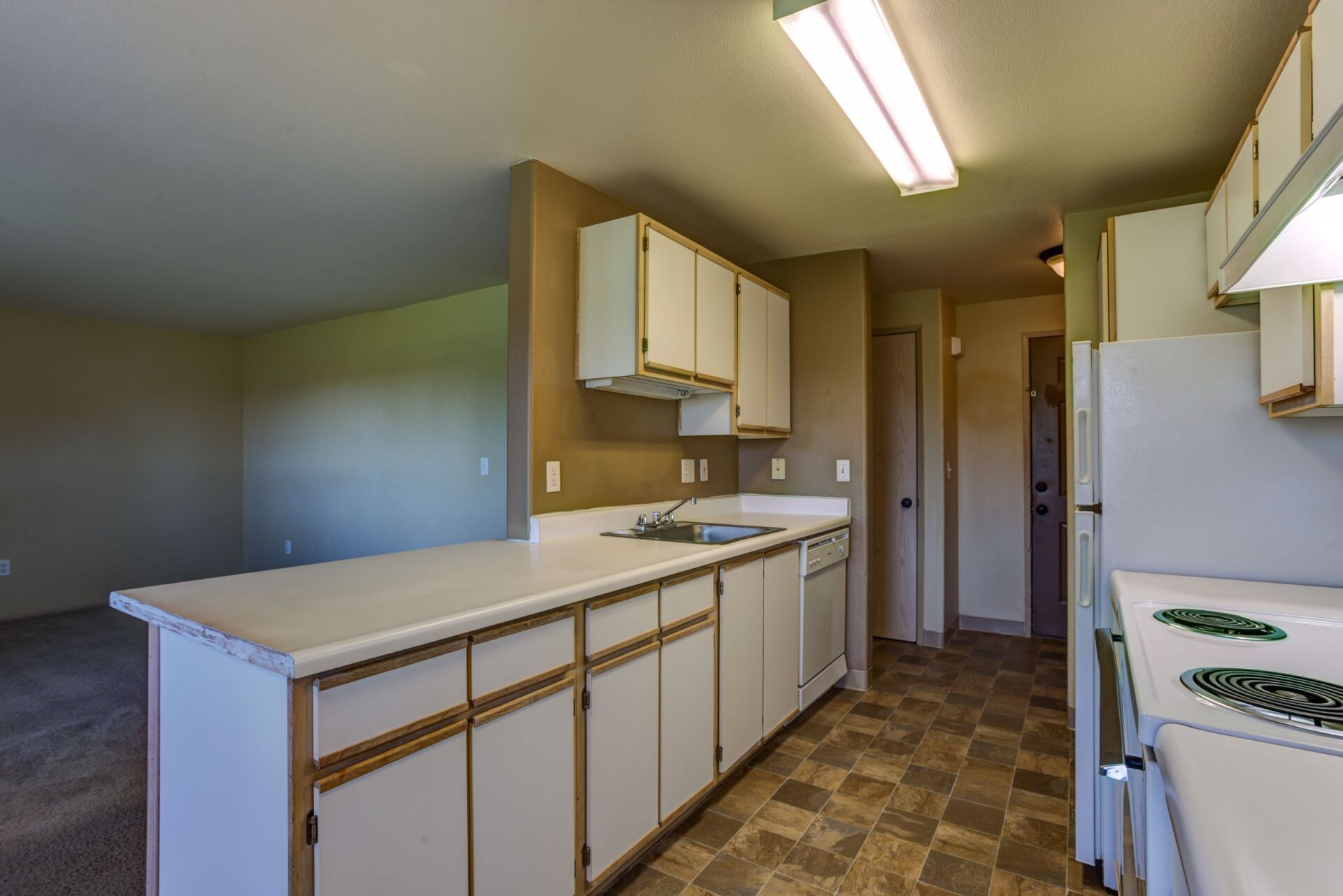 A kitchen with white cabinets , a stove and a refrigerator