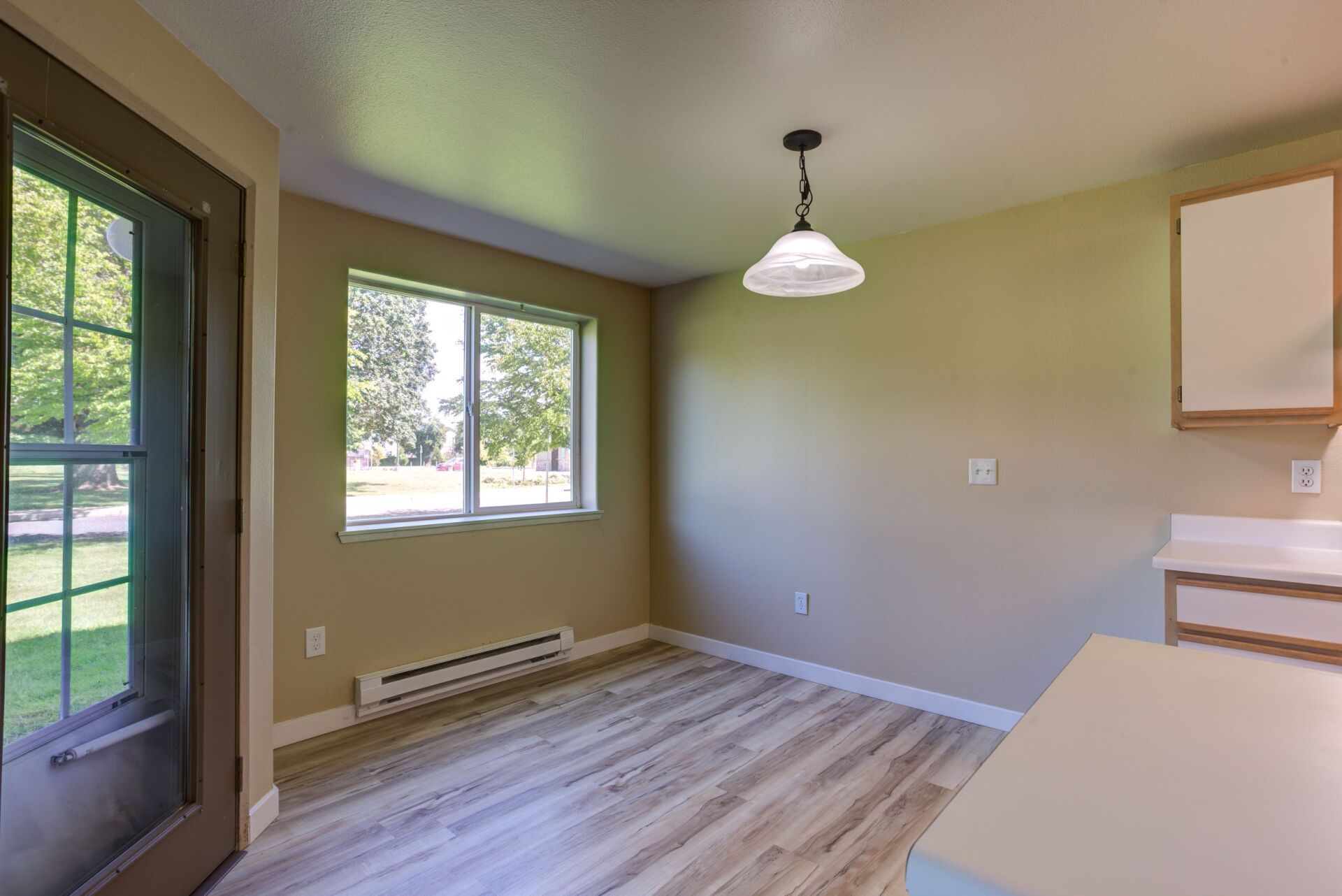 An empty room with hardwood floors and a sliding glass door.