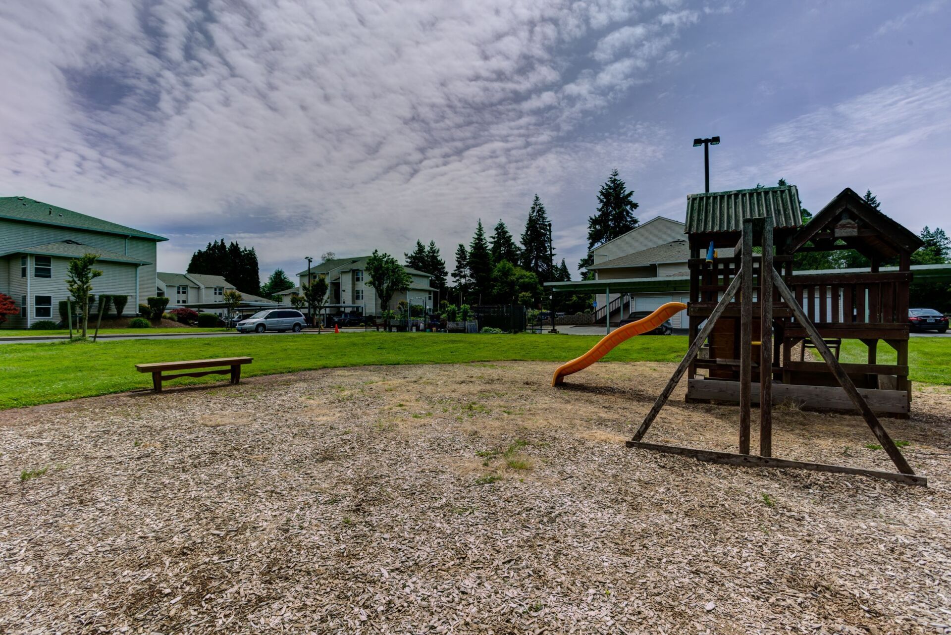 A playground with a slide and a picnic table in the background.
